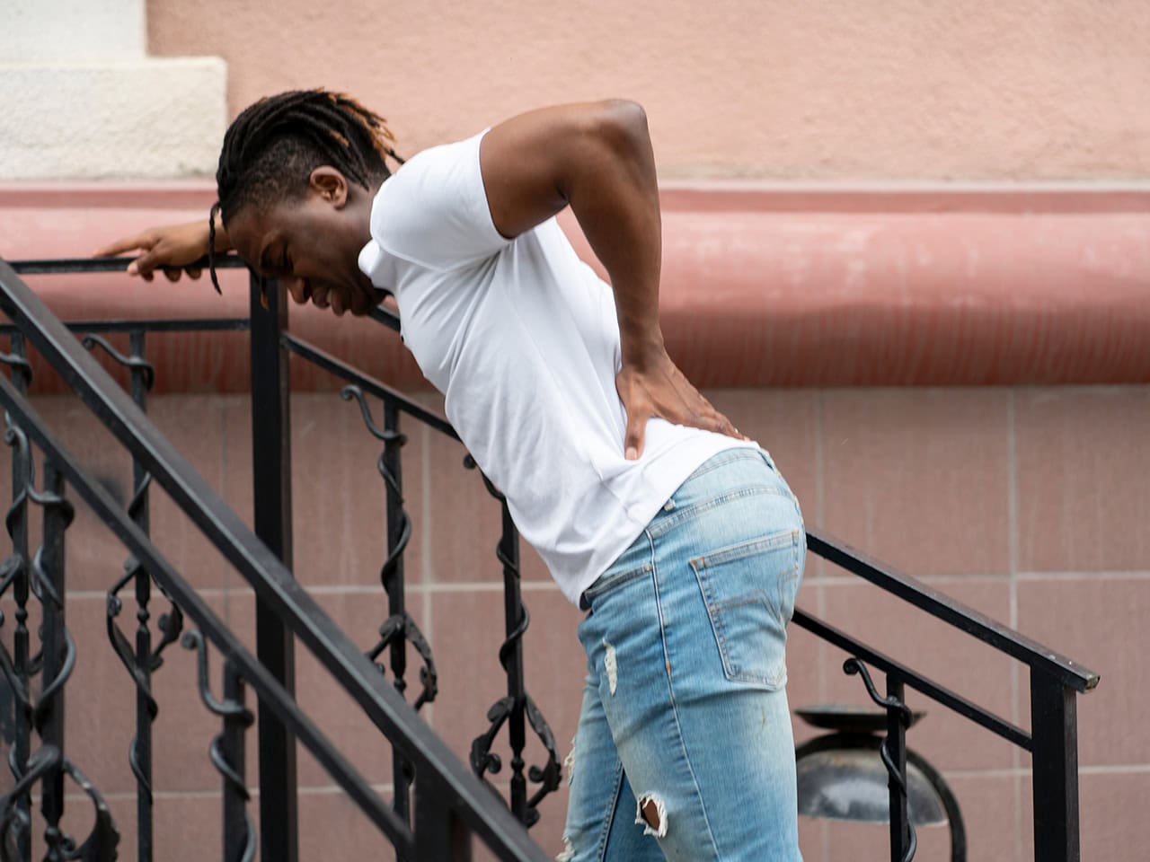 man going up stairs holding his back in pain