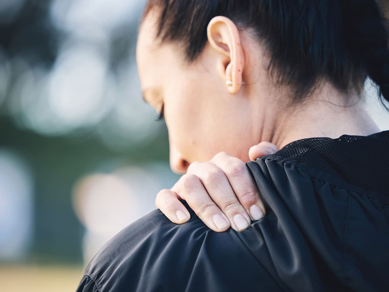 woman holding her shoulder in pain