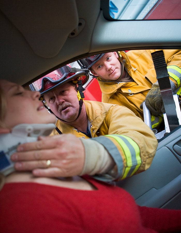 Firefighters helping woman from car accident injury